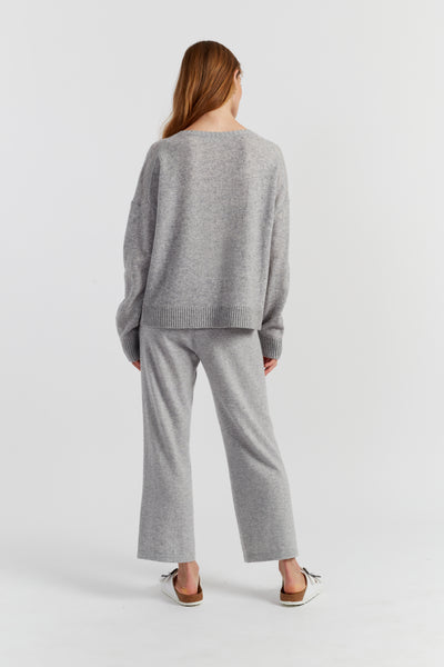Woman wearing a grey sweater and pants set on a white background