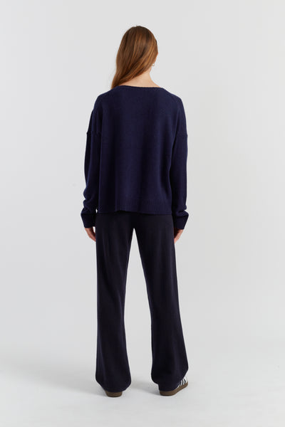 Person wearing a navy blue sweater and pants on a white background