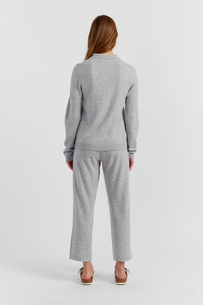 Person wearing a grey sweater and pants set on a white background