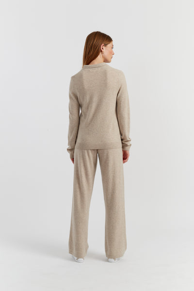 Woman wearing a beige sweater and pants set on a white background