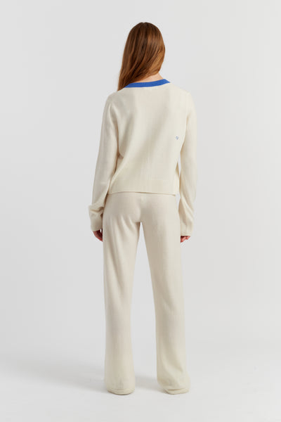Person wearing a cream outfit with a blue trim on a white background