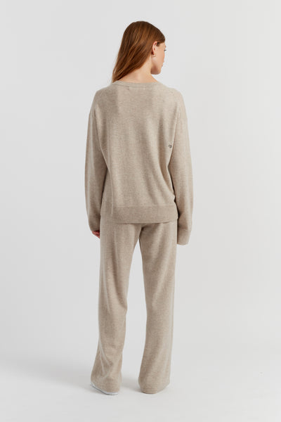 Woman wearing a beige sweater and pants set on a white background