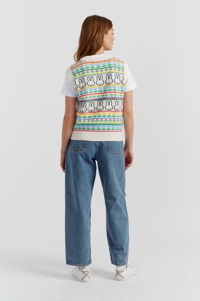 Person wearing a colorful patterned shirt and blue jeans on a white background