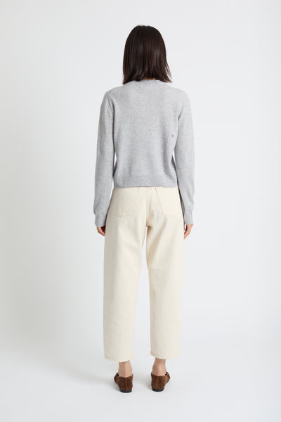 Person wearing a grey sweater and beige pants on a white background