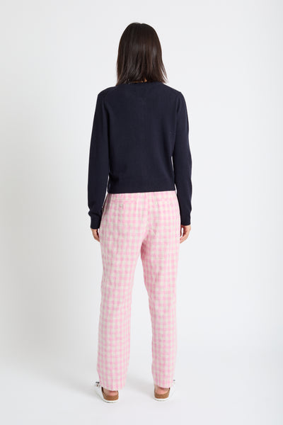 Person wearing a navy sweater and pink checkered pants on a white background