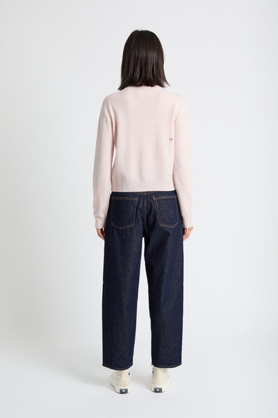 Person wearing a light pink shirt and dark blue jeans on a white background