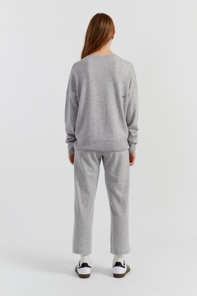 Person wearing a grey sweater and pants set on a white background