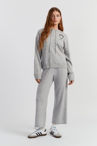 Woman wearing a grey tracksuit with Adidas shoes on a white background