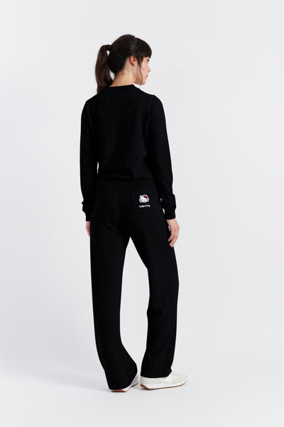 Person wearing a black tracksuit with a logo on a white background