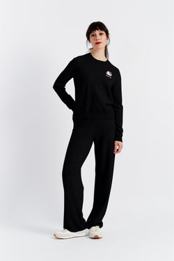 Person wearing a black outfit with a small logo on a white background