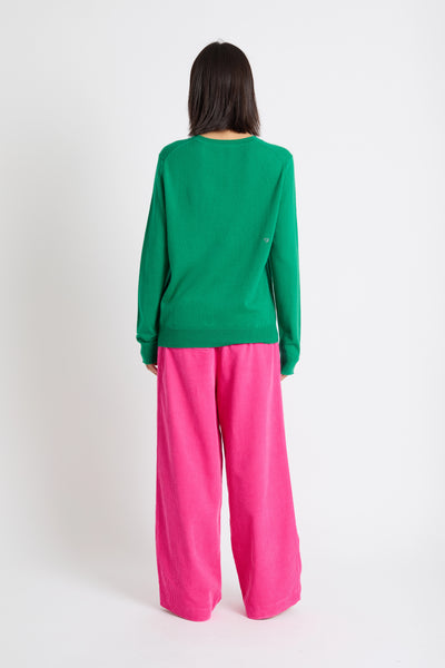 Person wearing a green sweater and pink pants on a white background