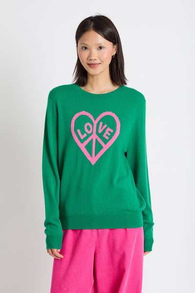 Person wearing a green sweater with a pink heart design on a white background