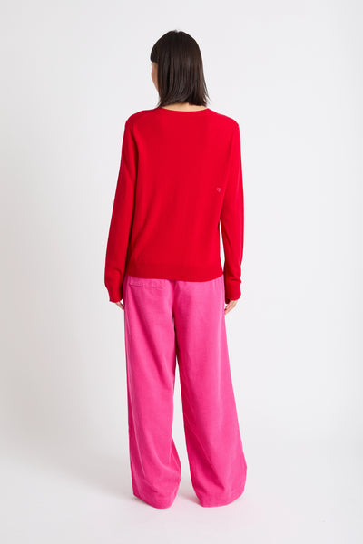 Person wearing a red sweater with a heart design and pink pants on a white background