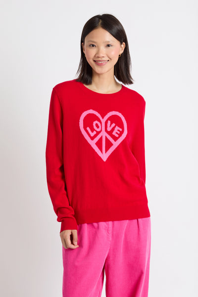 Person wearing a red sweater with a heart design and pink pants on a white background