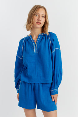 Woman wearing a blue outfit with embroidered details on a white background