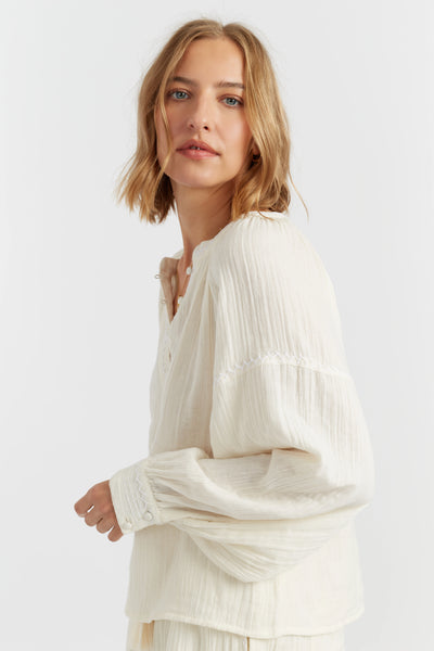 Woman wearing a white blouse with long sleeves on a plain background