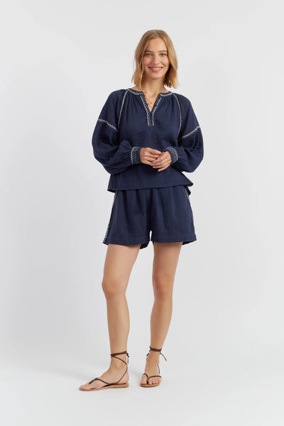 Woman wearing a navy blue outfit with white accents on a white background