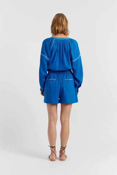 Woman wearing a blue outfit with white accents on a white background