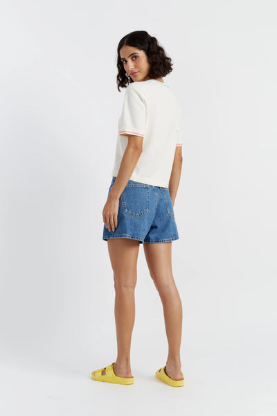 Woman wearing a white top and blue denim shorts on a white background