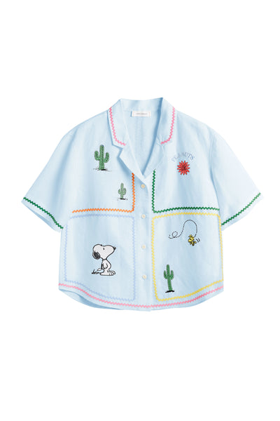 Light blue shirt with embroidered designs on a white background