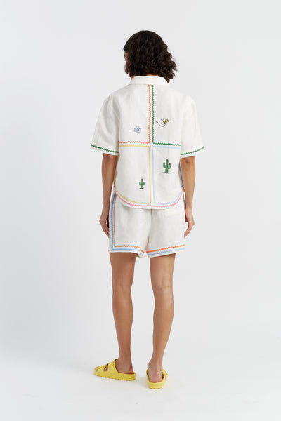 Person wearing a white outfit with colorful patterns on a white background