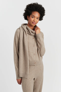 Woman wearing a beige knit cardigan and pants on a white background