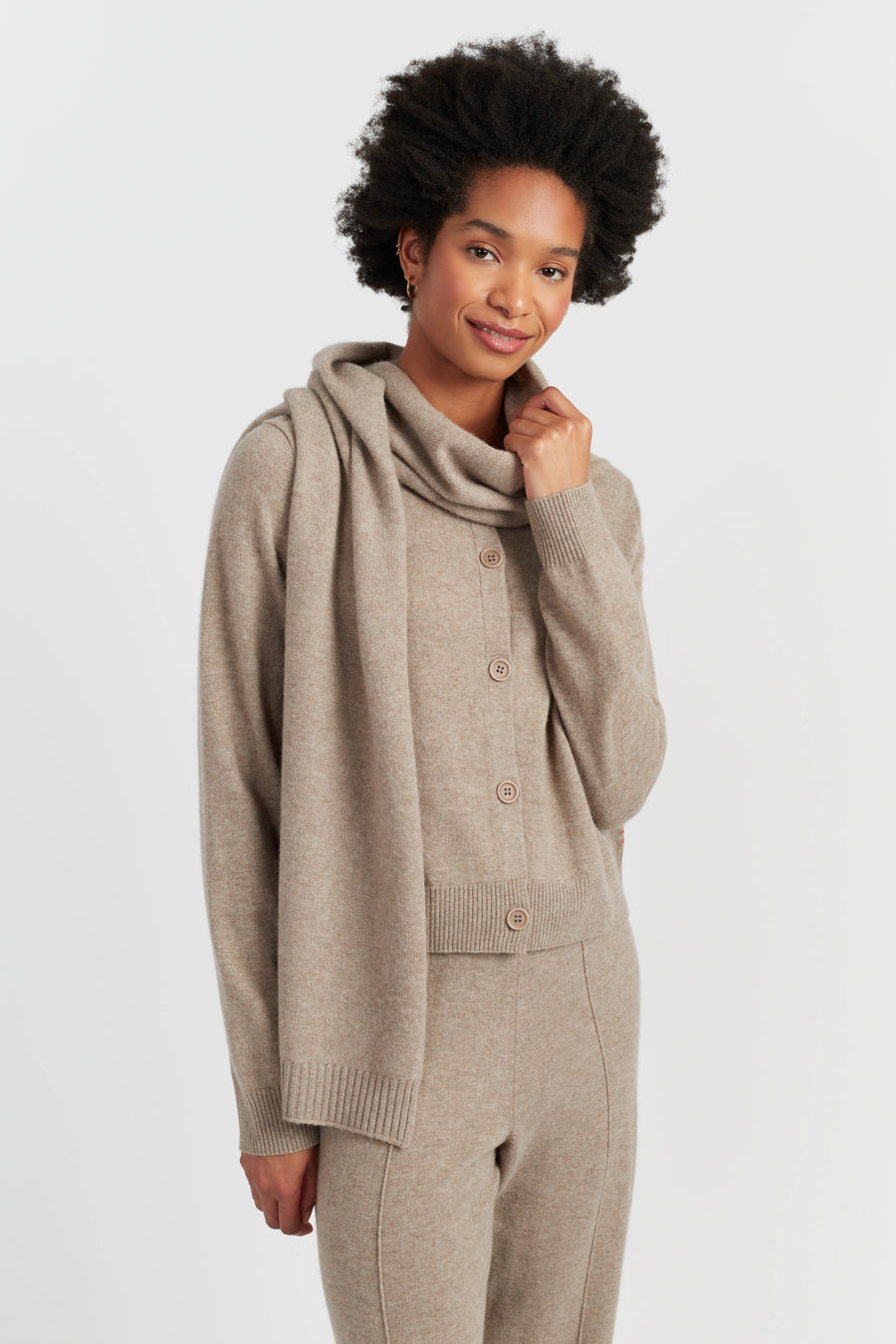 Woman wearing a beige knit cardigan and pants on a white background