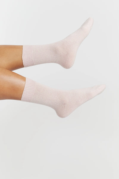 Light pink socks worn by a person on a light gray background