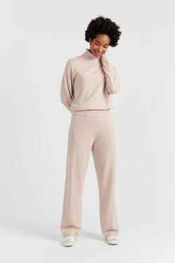 Person wearing a beige sweater and pants on a white background