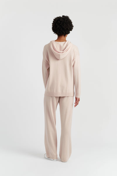 Person wearing a beige hoodie and pants on a white background