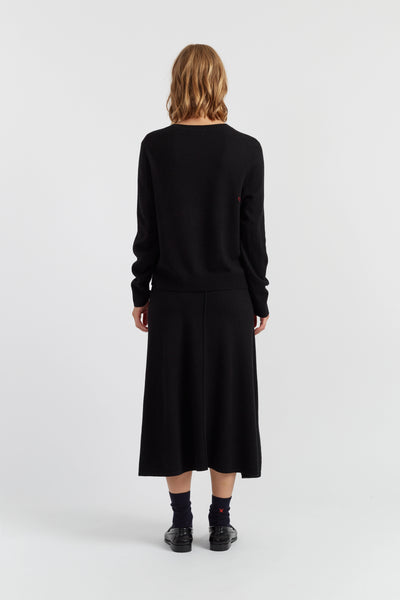 Person wearing a black sweater and skirt set on a white background