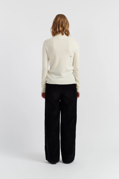 Person wearing a white sweater and black pants on a white background