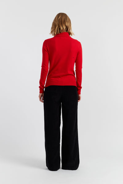 Person wearing a red sweater and black pants on a white background