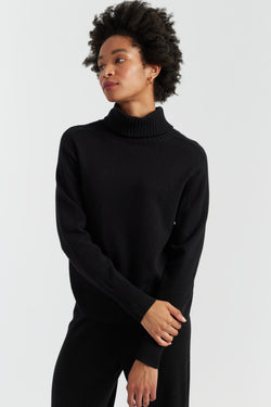 Woman wearing a black turtleneck sweater against a white background